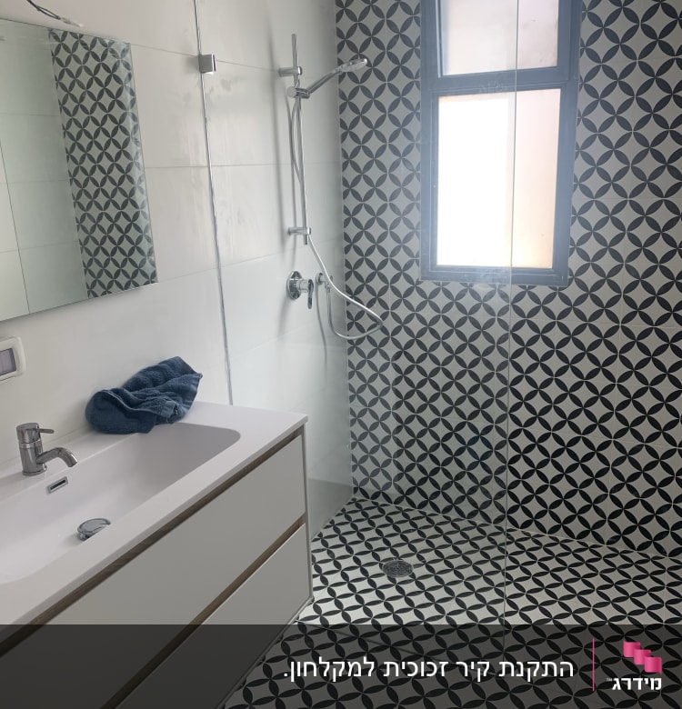 מקלחת עם ראש מקלחת, קיר זכוכית ורצפת אריחים מעוצבת